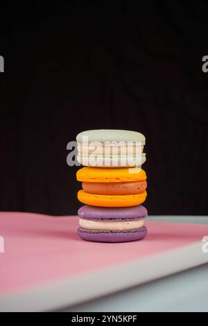 Una collezione di macaron colorati disposti su uno sfondo rosa tenue. La foto evidenzia la natura delicata e artistica di questo classico pas francese Foto Stock