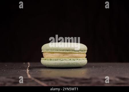 Una vista ravvicinata dei macaron color menta su sfondo nero, evidenziandone la consistenza gommosa e il dolce ripieno. Il concetto è adatto per il confectio Foto Stock