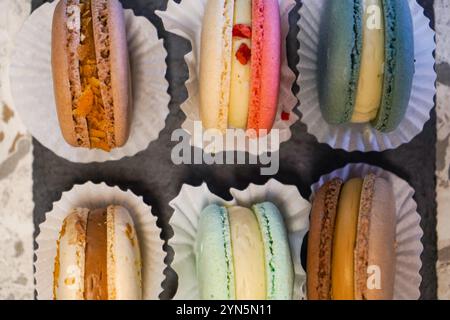 Un vivace assortimento di macaron colorati esposti su un piatto di ardesia. Perfetto per dessert, pasticceria francese e prelibatezze gourmet Foto Stock