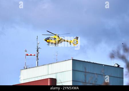 Augusta, Baviera, Germania - 24 novembre 2024: Un elicottero di soccorso giallo ADAC decolla dal tetto dell'ospedale universitario di Augusta per un'emergenza medica. Assistenza rapida e assistenza di emergenza efficiente nel soccorso aereo *** Ein gelber ADAC-Rettungshubschrauber startet vom Dach des Universitätsklinikum Augsburg zu einem medizinischen Notfall. Schnelle Hilfe und effiziente Notfallversorgung in der Luftrettung Foto Stock