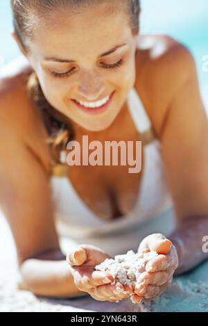 Felice giovane donna che gioca con la sabbia sulla spiaggia Foto Stock