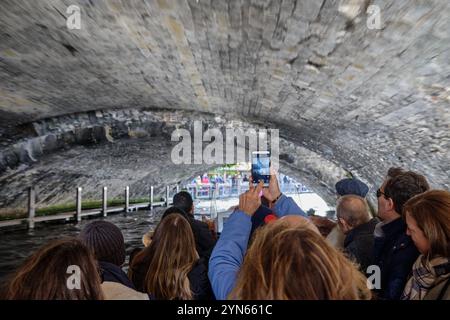 Turisti in un tour guidato dei canali nel centro storico di Bruges, nelle Fiandre occidentali, in Belgio, passando sotto un ponte Foto Stock