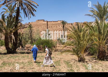 Terreno agricolo di fronte al pittoresco villaggio berbero di Tamenougalt nella valle del Draa, un turista condotto da un berbero al villaggio, Marocco, Africa Foto Stock