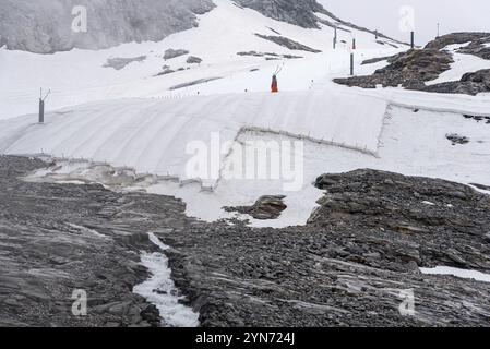 Una grande tela bianca che protegge il ghiaccio del ghiacciaio dell'Hintertux nelle Alpi, una pista da sci conduce tra l'Austria e l'Europa Foto Stock