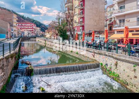 Fiume Sakoulevas con edifici residenziali e caffè sul marciapiede lungo la costa. A Florina, Macedonia, Grecia. Foto Stock