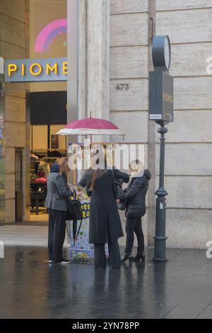 Roma, Italia. 22 novembre 2024. Alcune donne di un venditore ambulante che vende biglietti Lotteria Italia in via del corso acquistano i loro biglietti in una mattina di novembre a Roma. Anche quest'anno, è iniziata la vendita dei biglietti per la lotteria italiana, che ogni anno accompagna italiani e turisti nei loro sogni durante il periodo natalizio fino al 6 gennaio (lo scorso 16 settembre). Per rilanciare la lotteria, la Commissione Finanze del Senato ha proposto, all'inizio del 2024, di valutare l'estrazione dei biglietti vincitori non più il 6 gennaio, come da tradizione, ma nelle serate del Festival di Sanremo (Jus Foto Stock