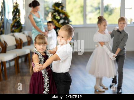 Bambini preadolescenti in abiti eleganti che praticano la danza di coppia nello studio natalizio Foto Stock