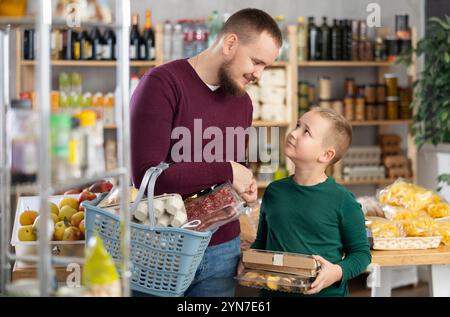 Giovane con figlio che sceglie la spesa in negozio Foto Stock