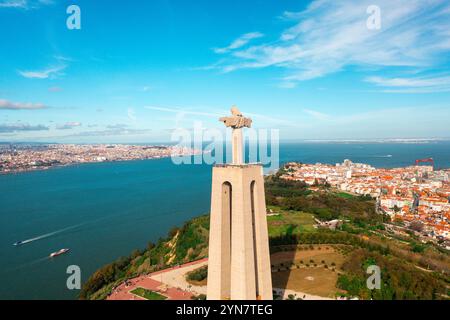 Veduta aerea del monumento Santuario del Cristo Re. Maestosa statua panoramica che si affaccia sulla città di Almada e sul fiume Tago. Vista dall'alto sul monumento cattolico e sulla città. Foto Stock