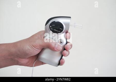 Rilevatore analizzatore di respirazione ad alcool Man Holding Digital Breathalyzer. Per misurare il contenuto alcolico nel sangue non bere e guidare il concetto con il seno Foto Stock