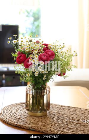 Bellissimi fiori di ranunculus e camomille in vaso sul tavolo all'interno Foto Stock