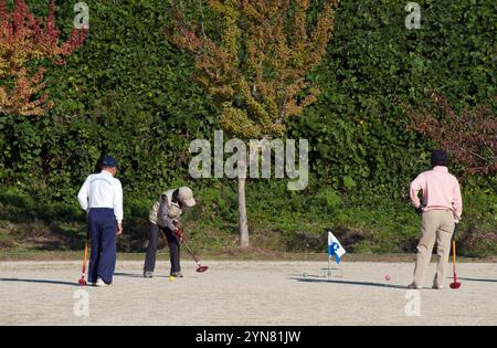 Gruppo di anziani giapponesi che giocano a "gateball" (croquet) in un pomeriggio di sole a Hikone, prefettura di Shiga, Giappone. Foto Stock