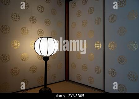 Lanterna ovale a pavimento luminoso nell'angolo accanto a porte fusuma scorrevoli ornate all'interno della villa Seisonkaku a Kanazawa, Ishikawa, Giappone. Foto Stock