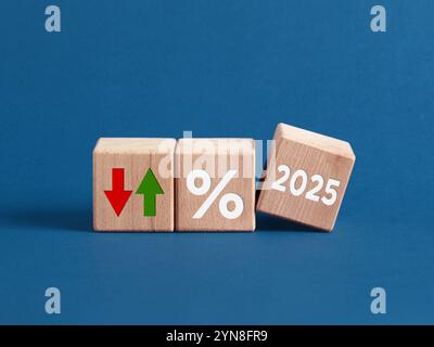 Cubi di legno che mostrano il simbolo percentuale e frecce fluttuanti che suggeriscono variazioni del tasso di interesse nel 2025. Foto Stock