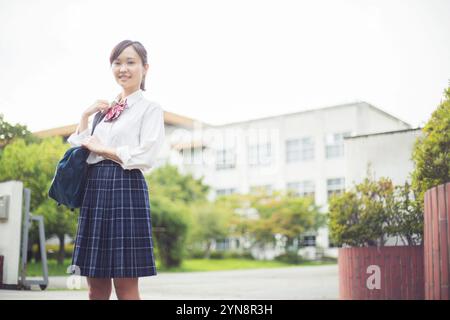 Liceale in piedi davanti al cancello della scuola Foto Stock