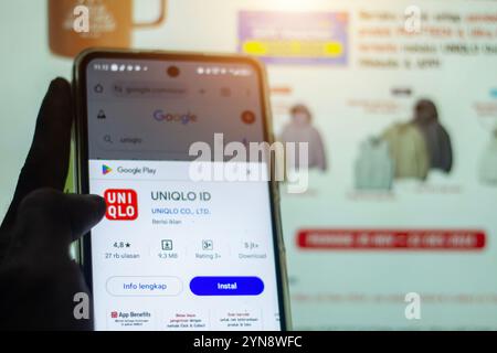 Pringsewu, Lampung; 25 novembre 2024; primo piano della mano umana, icona dell'id dell'app uniqlo sullo schermo dello smartphone primo piano, uniqlo id è l'app per lo shopping sul computer Foto Stock
