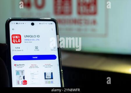 Pringsewu, Lampung; 25 novembre 2024; primo piano della mano di un uomo installare l'icona dell'id dell'app uniqlo sullo schermo dello smartphone primo piano, uniqlo id è l'app di shopping Foto Stock