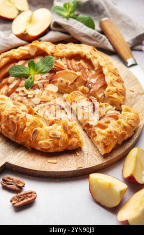 galette di mele appena sfornata, decorata con scaglie di mandorle e foglie di menta, servita su una tavola di legno Foto Stock