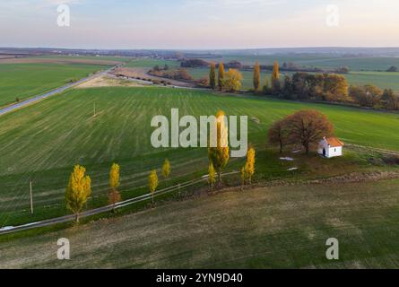 Paesaggio sui campi al tramonto con cappella, vista aerea Foto Stock
