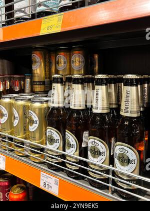 Kiev, Ucraina - 24 novembre 2024: Una varietà di bottiglie e lattine di birra Warsteiner esposte su uno scaffale di un supermercato, con la loro confezione e pric Foto Stock