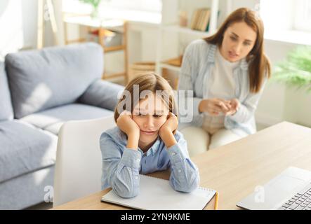 Stanco, frustrato, annoiato adolescente, madre che rimprovera il bambino, ragazzo a casa, studente scolastico che sente fatica Foto Stock