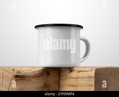 Mockup di tazza in smalto bianco con bordo nero, su trave in legno vecchio testurizzato, tazza in metallo sulla parte superiore del legno, per design, branding. Presentazione della templ di tazza di ferro Foto Stock