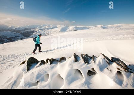 Il Lake District Le montagne in inverno la neve da Red ghiaioni, con una femmina di hill walker, UK. Foto Stock