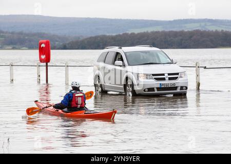 Kayak e auto in una strada allagata di Storth all'estuario del fiume Kent Foto Stock