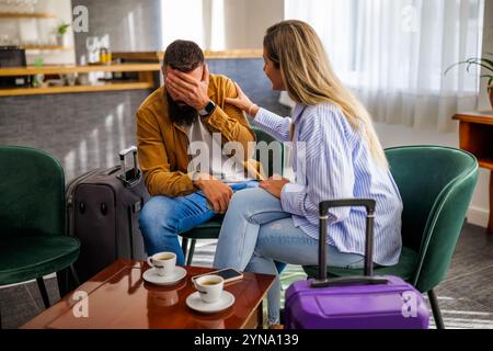 La giovane coppia va in vacanza. Turisti seduti al bar dell'aeroporto a causa del ritardo del volo. Foto Stock