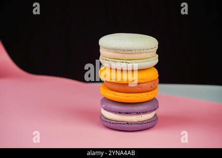 Una collezione di macaron colorati disposti su uno sfondo rosa tenue. La foto evidenzia la natura delicata e artistica di questo classico pas francese Foto Stock