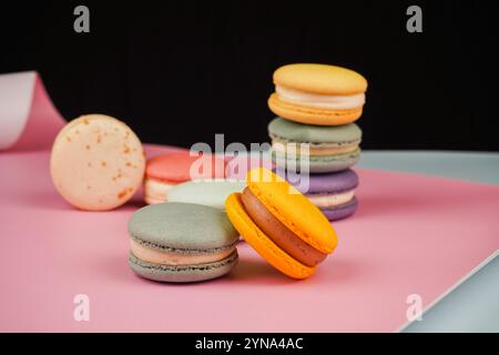 Una collezione di macaron colorati disposti su uno sfondo rosa tenue. La foto evidenzia la natura delicata e artistica di questo classico pas francese Foto Stock