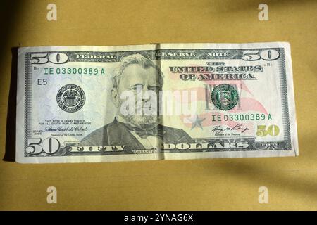 Soldi americani, una banconota, 50 cinquanta dollari con carta di credito sono situati su uno sfondo marrone lucido. Foto Stock