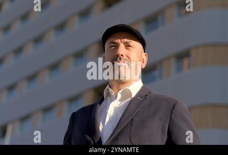 Ritratto di un uomo elegante con cappello che guarda in lontananza nella città con edifici sullo sfondo Foto Stock