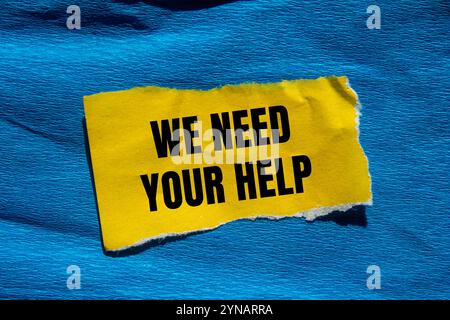 Abbiamo bisogno del tuo messaggio di aiuto scritto su un pezzo di carta giallo strappato con sfondo blu. Concettuale abbiamo bisogno del tuo simbolo di aiuto. Copia spazio. Foto Stock