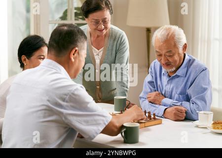 gruppo di giovani asiatici felici due coppie che si riuniscono a casa giocando a scacchi insieme Foto Stock