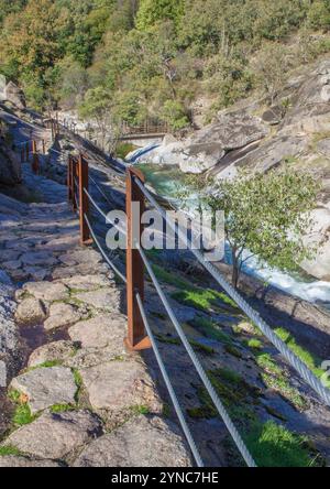 Percorso semi-scavato nella roccia con il ponte pedonale Los Pilones sul fondo. Estremadura, Spagna Foto Stock