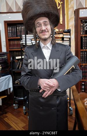 Foto in posa di un ebreo ortodosso che indossa un cappello in pelliccia streimel e tiene in mano un megillah in una cassa. A Brooklyn, New York. Foto Stock