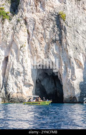 I turisti che visitano l'isola greca di Zante o Zante utilizzano una piccola barca a noleggio o a noleggio per esplorare le grotte sulla costa di Keri, attrazioni turistiche Foto Stock