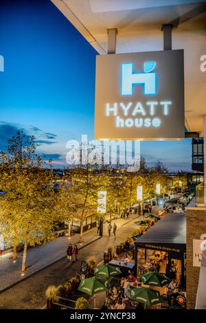 Hyatt House Hotel The Wharf Washington DC | WASHINGTON DC, Stati Uniti - un cartello illuminato di Hyatt House pende sopra la passeggiata al Wharf nel Southwest DC, con i commensali riuniti sotto gli ombrelli verdi al Kirwan's Irish Pub sotto. Il Wharf è uno sviluppo misto lungo il canale di Washington che si è aperto in fasi a partire dal 2017. L'Hyatt House per soggiorni prolungati offre camere in stile appartamento con vista sul Canale e sullo skyline del quartiere. Foto Stock