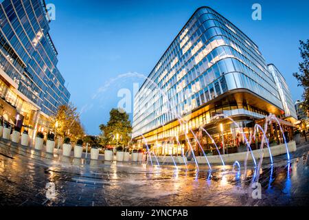 WASHINGTON DC, Stati Uniti - fontane interattive e giochi d'acqua animano gli spazi plaza al Wharf, un quartiere sul lungomare ristrutturato nel sud-ovest di Washington DC, mentre il crepuscolo si deposita sullo sviluppo ad uso misto. Edifici moderni incorniciano le esposizioni d'acqua, che offrono sia fascino estetico che spazi pubblici di ritrovo. Foto Stock