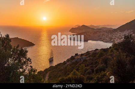 Vista del tramonto dorato sul mare Adriatico vicino alla città vecchia di Dubrovnik con yacht a vela in primo piano. Foto Stock