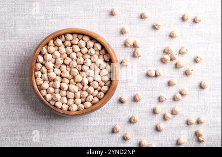 Ceci essiccati in un recipiente di legno, su tessuto di lino, dall'alto. Ceci conciati interi e leggeri, ricchi di legumi proteici e frutti di Cicer arietinum. Foto Stock