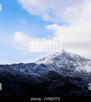 Picco del Monte Snowdon (Yr Wyddfa), Snowdonia (Eryri), Galles, coperto di neve in una nuvolosa giornata invernale con un po' di cielo blu. Foto Stock