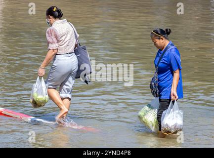 SAMUT PRAKAN, THAILANDIA, 19 novembre 2024, Una donna con passeggiate per lo shopping attraverso strade allagate Foto Stock