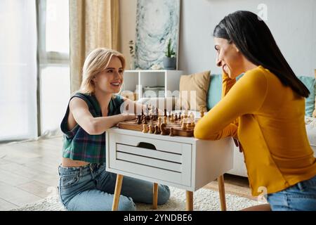 Due giovani donne condividono un momento caldo mentre giocano a scacchi insieme a casa loro. Foto Stock