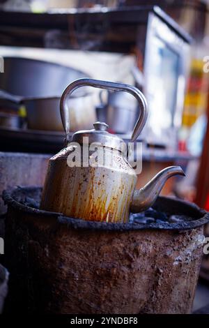 Preparazione del tè nel bollitore (sul forno a carbone). Questo è il modo in cui i venditori locali di tè di strada in India preparano il tè e lo servono alla gente in stile tradizionale. Foto Stock