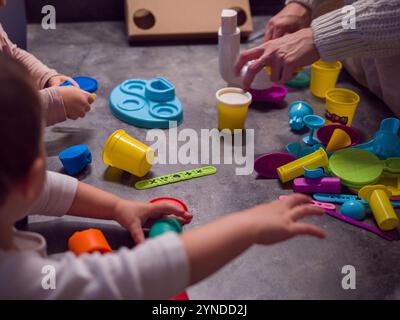 I bambini si impegnano in un gioco creativo, utilizzando l'argilla vibrante e vari strumenti di plastica, sviluppando le loro abilità motorie e l'immaginazione Foto Stock