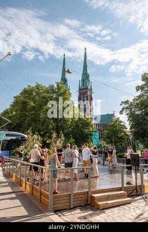 Persone che ballano nelle strade estive si esibiscono in un palco di eventi nella Piazza del Museo del Design nel quartiere Ullanlinna di Helsinki, Finlandia Foto Stock