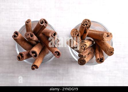 Bastoncini di cannella Cassia e Ceylon in occhiali su tessuto di lino. Cinnamomum cassia sulla sinistra e Cinnamomum zeylanicum sulla destra. Foto Stock