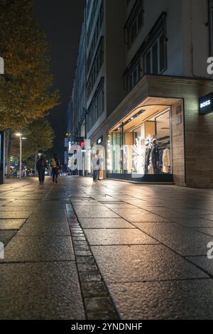 Scena notturna di strada con vetrine illuminate, marciapiedi bagnati e atmosfera autunnale, Stoccarda, Germania, Europa Foto Stock